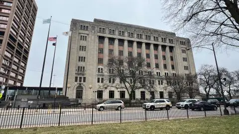 Historic building with flags and surrounding trees.