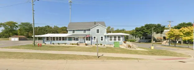 Light blue house with porch and green bin.